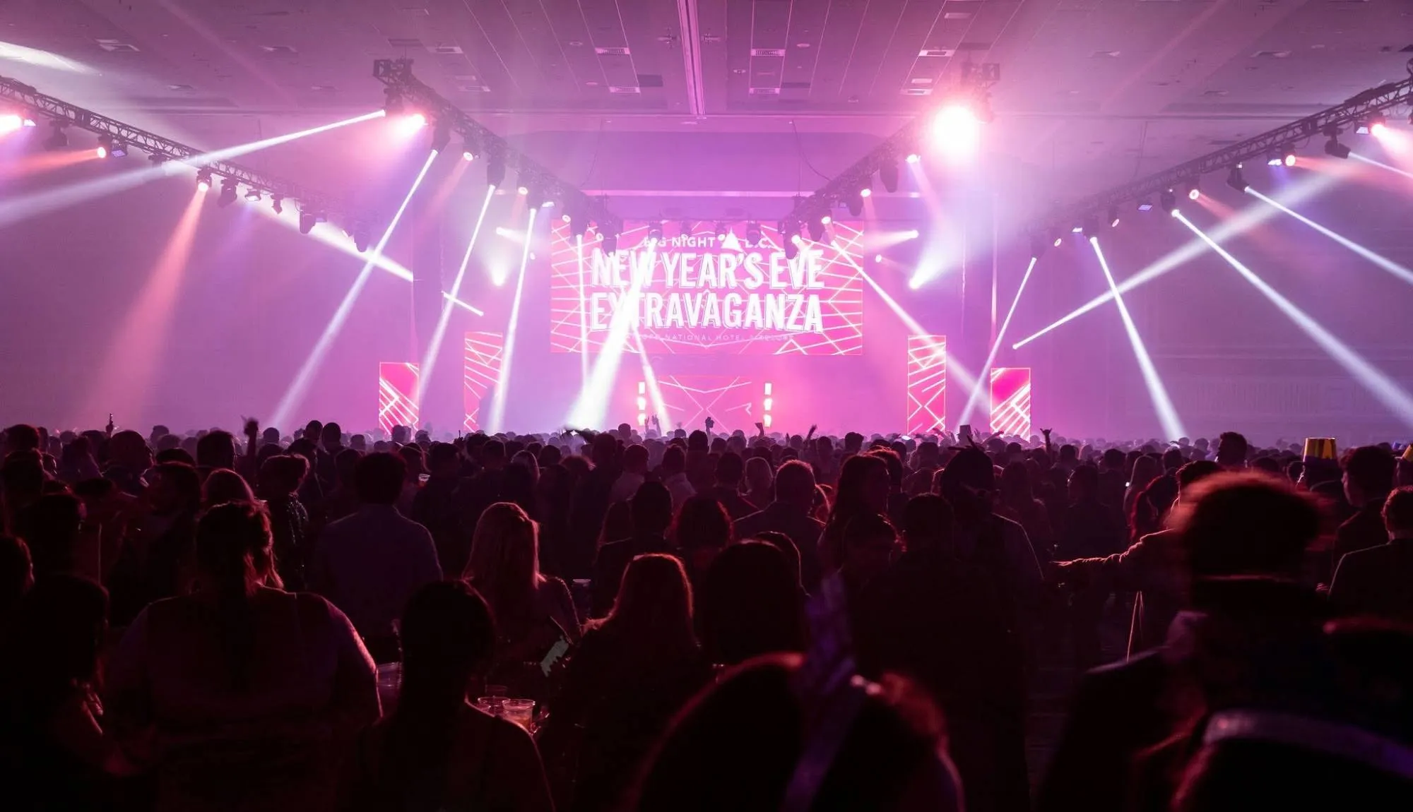 Big Night D.C. New Year’s Eve Extravaganza at the Gaylord National: light beams sweep a packed ballroom toward the stage
