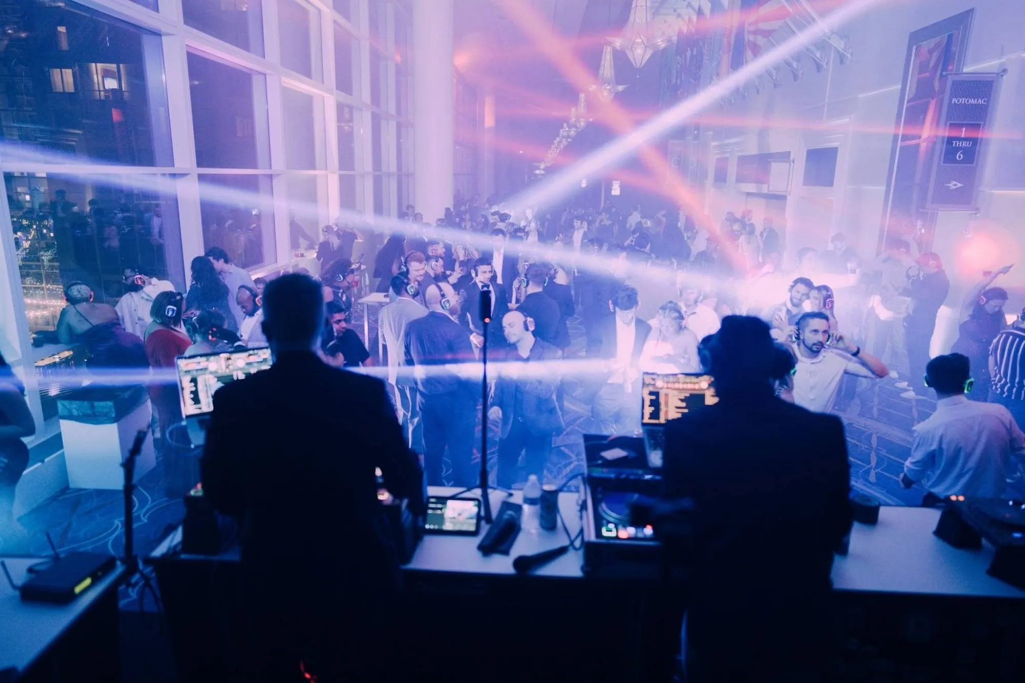 Big Night New Year’s Eve silent disco: two DJs play to guests in glowing headphones under crossing light beams