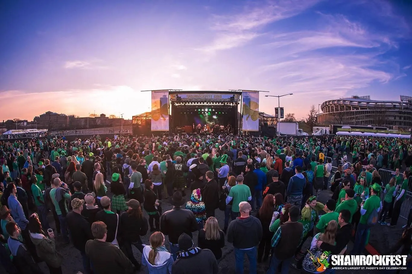 ShamrockFest main stage at sunset, a crowd in green in front and RFK Stadium behind it in Washington, D.C.