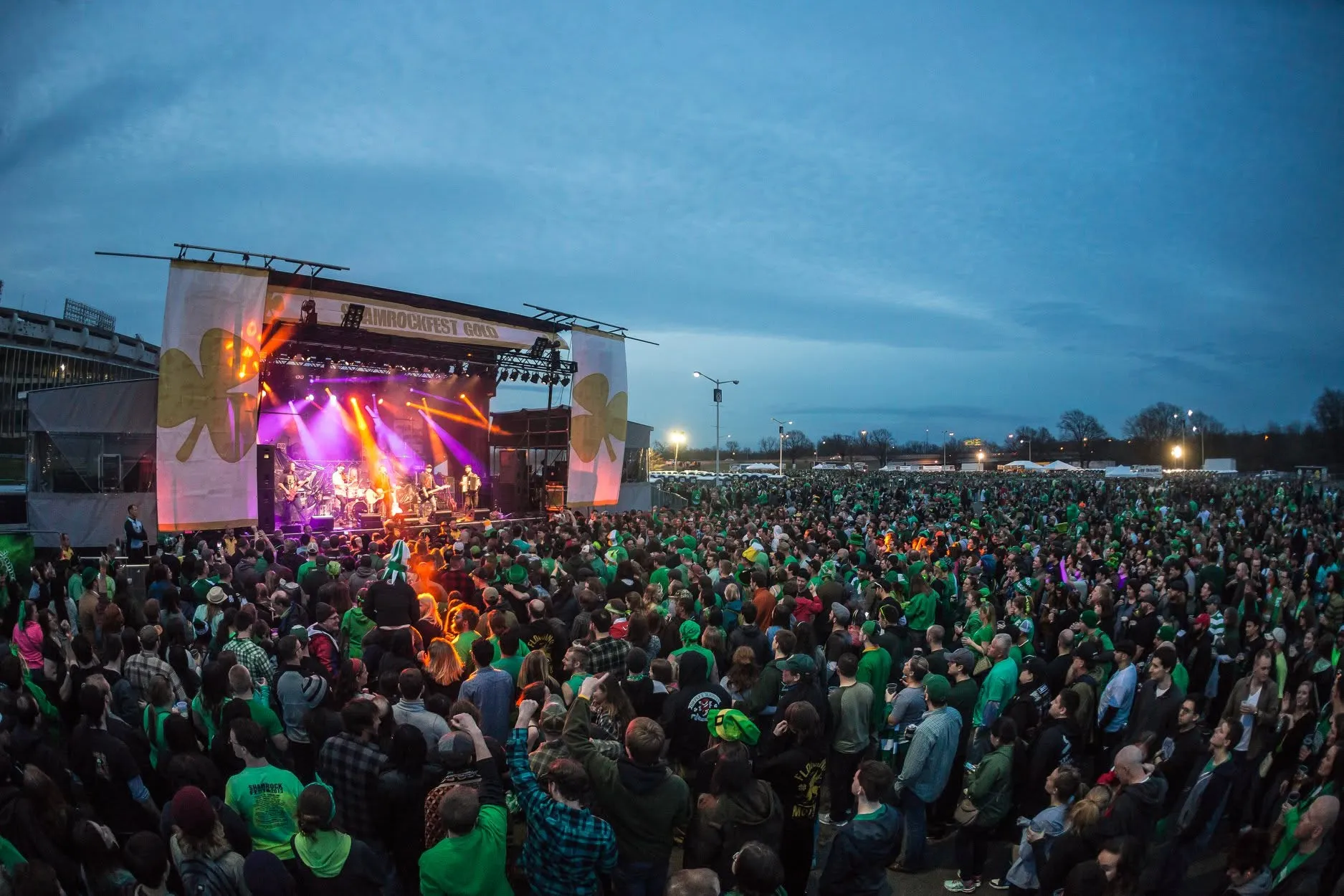 ShamrockFest in Washington, D.C.: a crowd in green fills the grounds at the main stage at dusk beside RFK Stadium